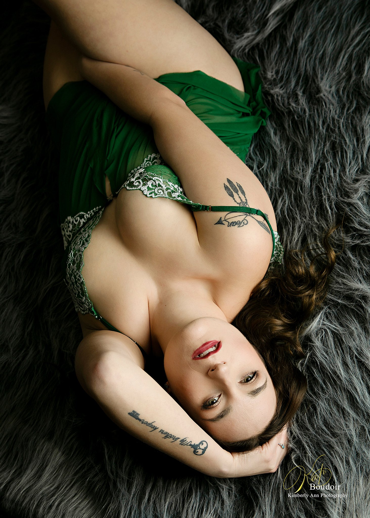 A woman in a green slip lays on a fur blanket with a hand between her legs and the other in her hair before doing some chicago date night ideas