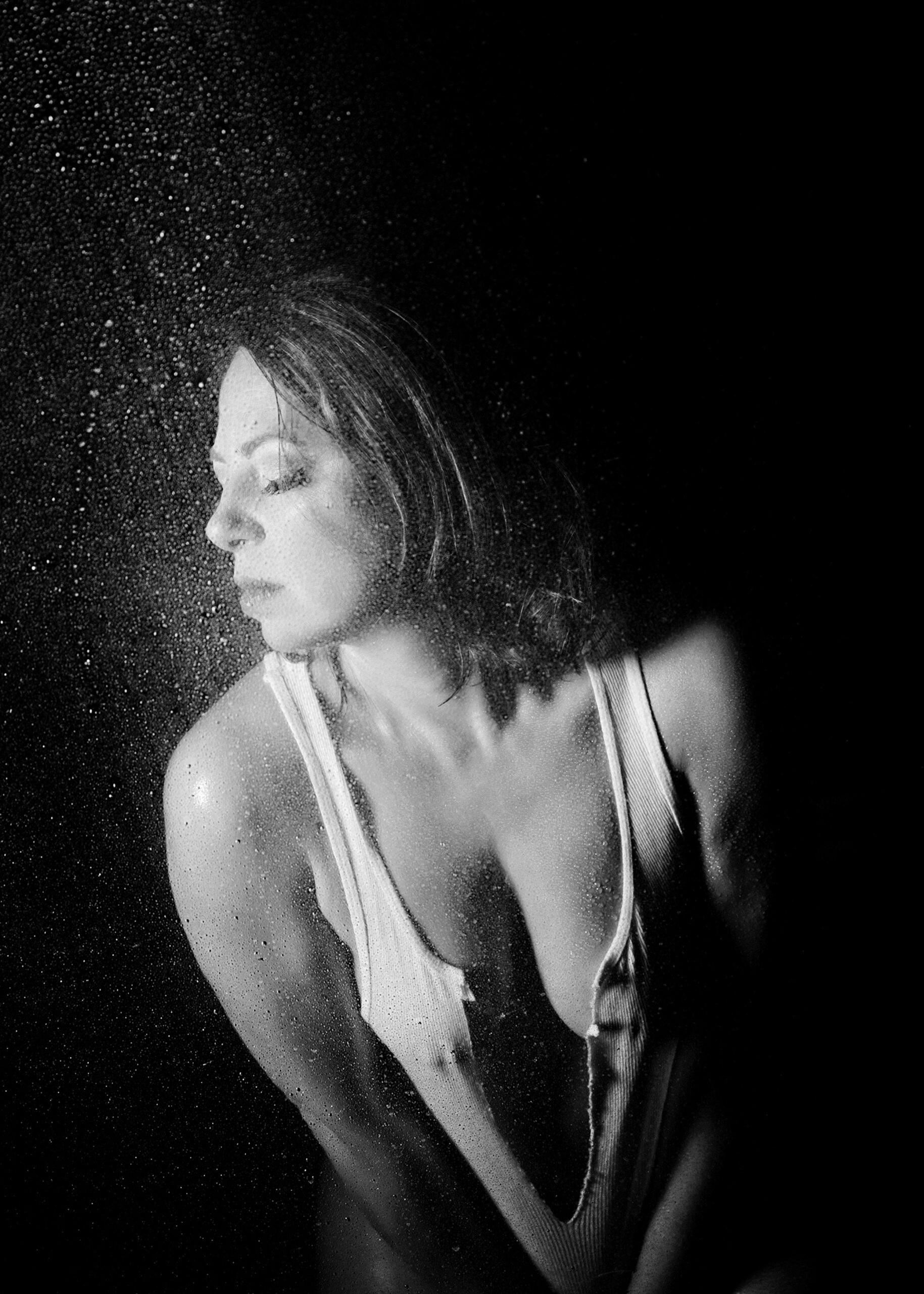 A woman in a ripped white shirt leans over in a dark shower in a studio during her madison wi bachelorette party