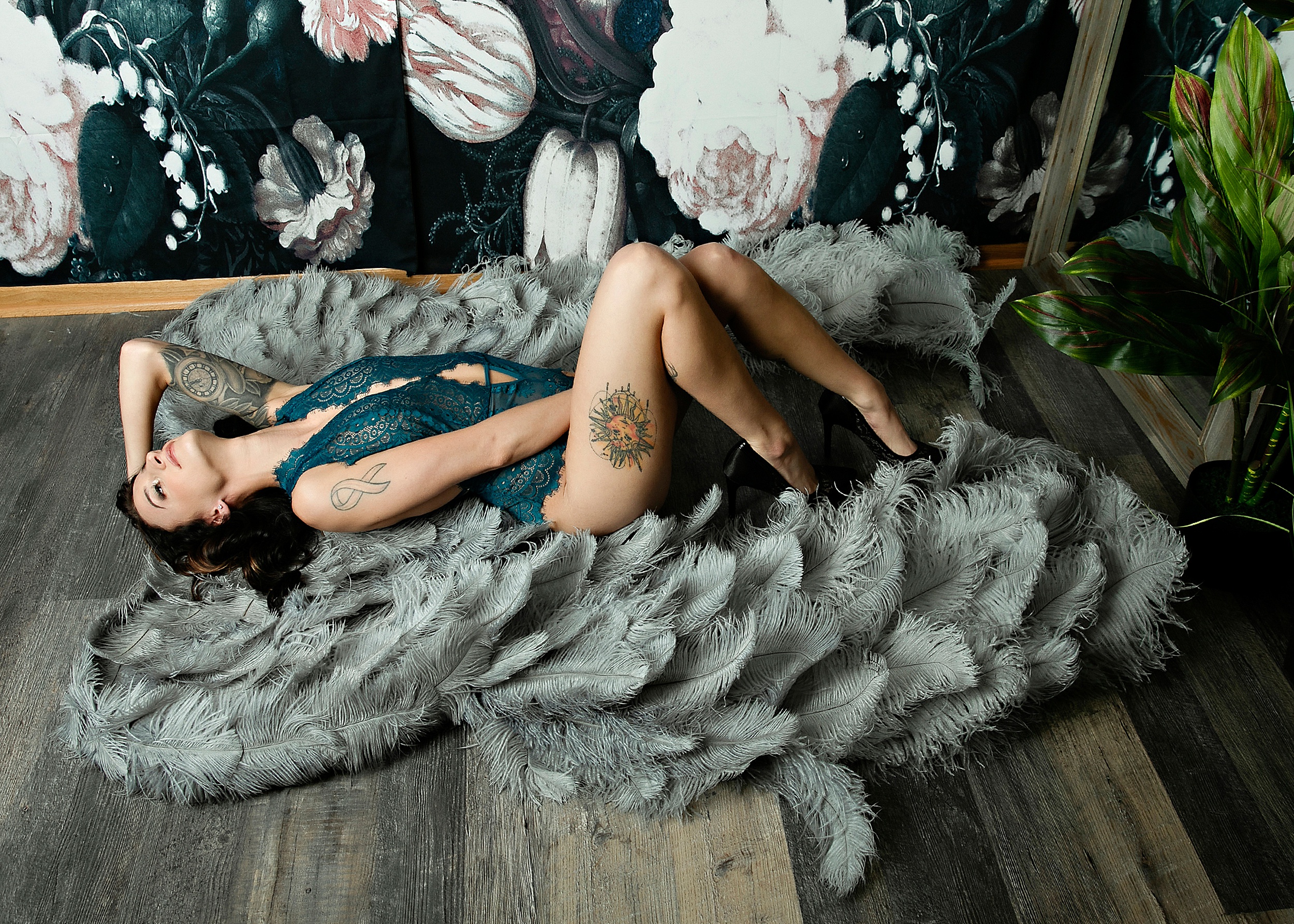 A woman in blue lingerie and tattoos lays on the floor of a studio with knees up and a hand in her hair before visiting romantic restaurants madison wi